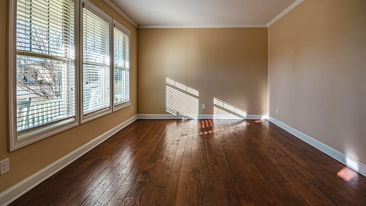 An empty room in Troy with new dark hardwood flooring laid straight to the walls